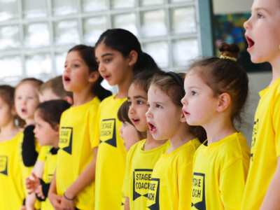 Row of Early Stages children in yellow Stagecoach T-shirts singing together