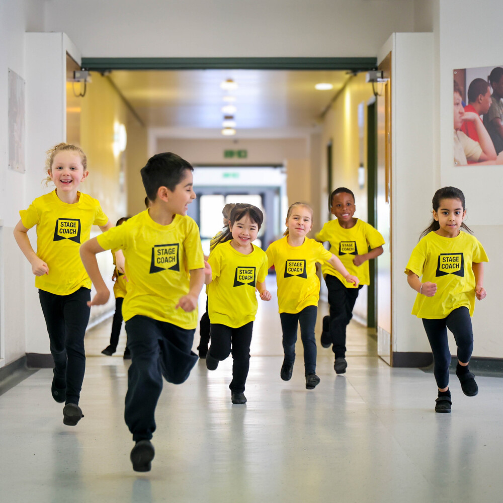 Early Stages children in yellow Stagecoach T-shirts running down a hallway