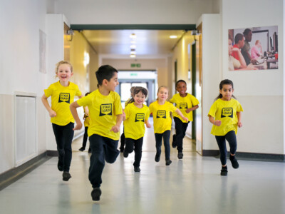 Early Stages children in yellow Stagecoach T-shirts running down a hallway