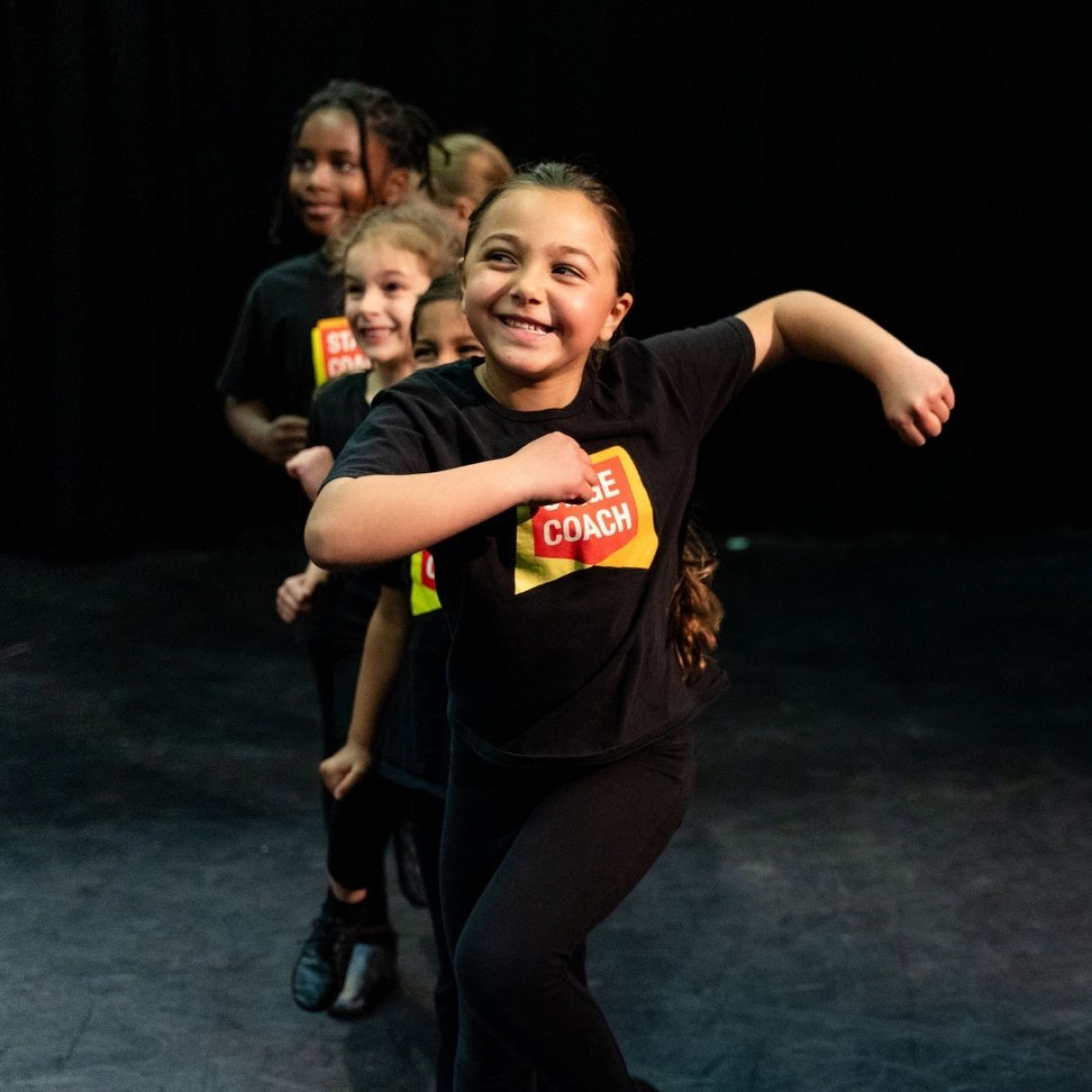 Children performing together in a Stagecoach performing arts class.